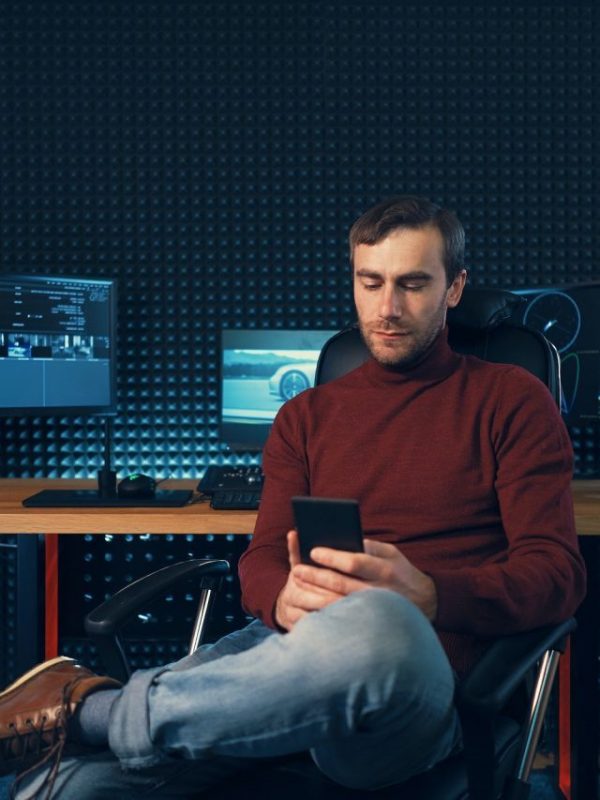 Young man working in the studio using a smartphone and computer.